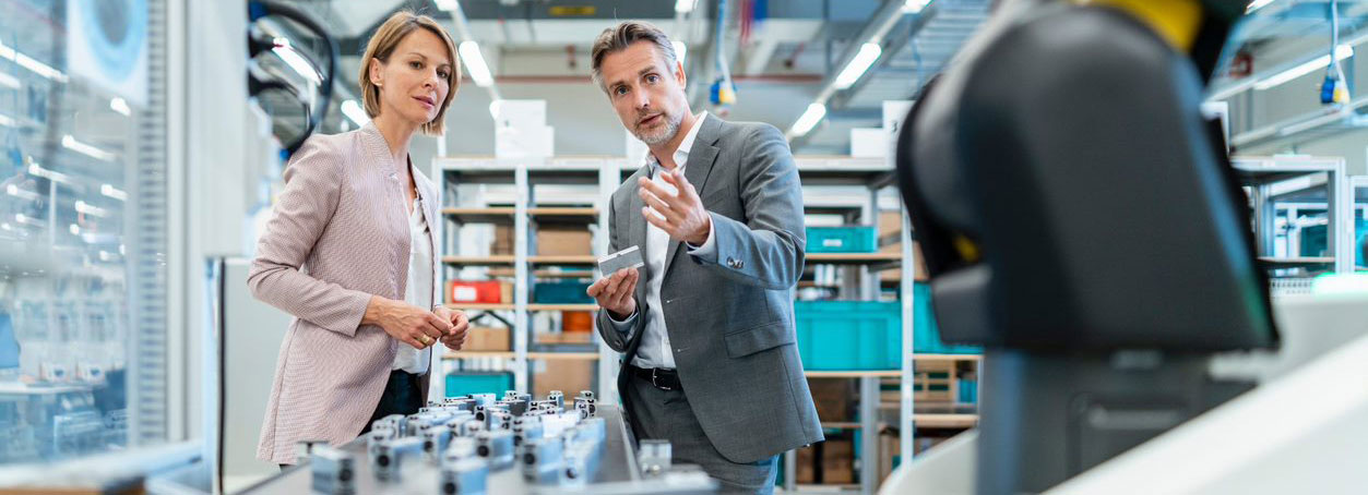 Business man and business woman talking in a modern factory hall